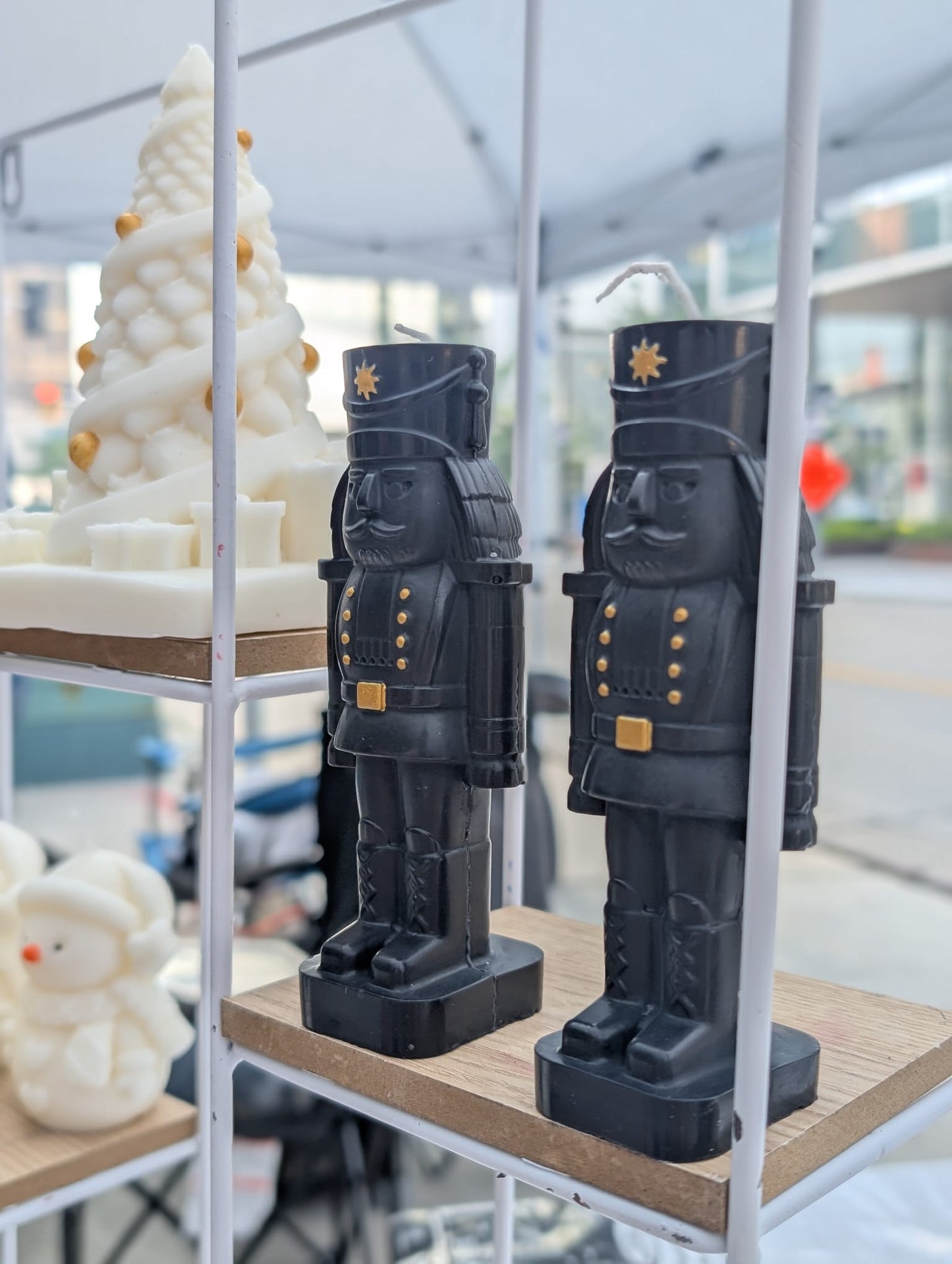 Two black nutcracker figurines on a wooden shelf with a blurred outdoor background.