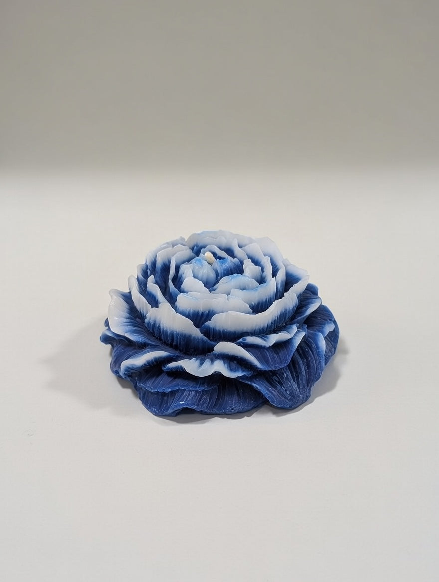 Blue and white flower-shaped candle on a light gray background
