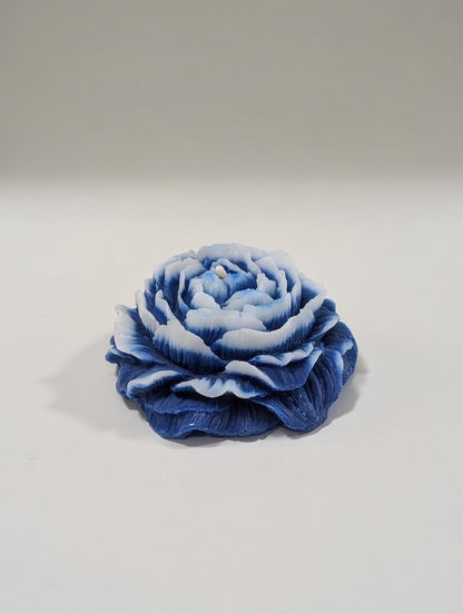 Blue and white flower-shaped candle on a light gray background