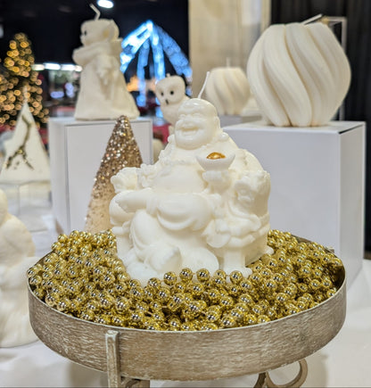 White Buddha statue on a bed of gold beads in a decorative setting with other similar statues.