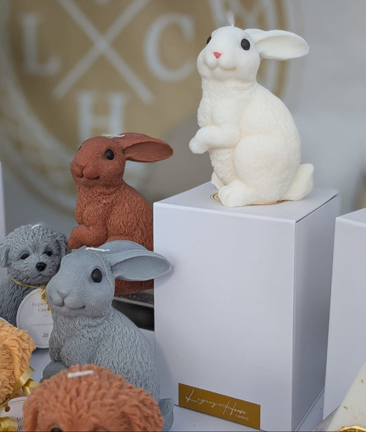 Collection of rabbit figurines in various colors with a blurred logo in the background.