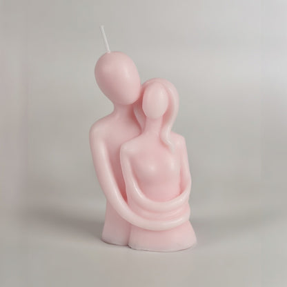 Pink candle shaped like a couple on a plain background