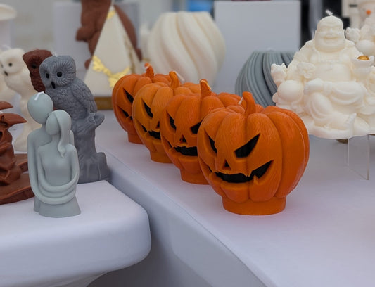 Display of Halloween-themed soy wax figurines including pumpkins and ghosts on a white surface.
