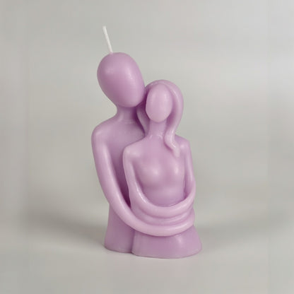 Purple candle shaped like two people embracing on a plain background