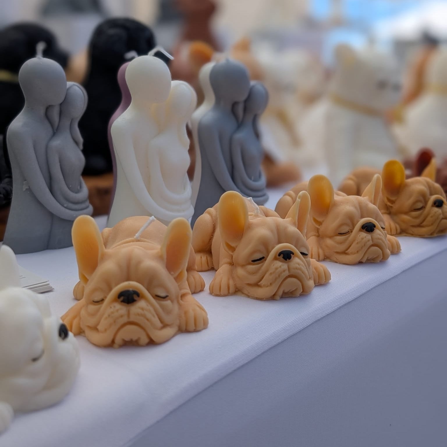 Row of french bulldog shaped candles on a table with a blurred background