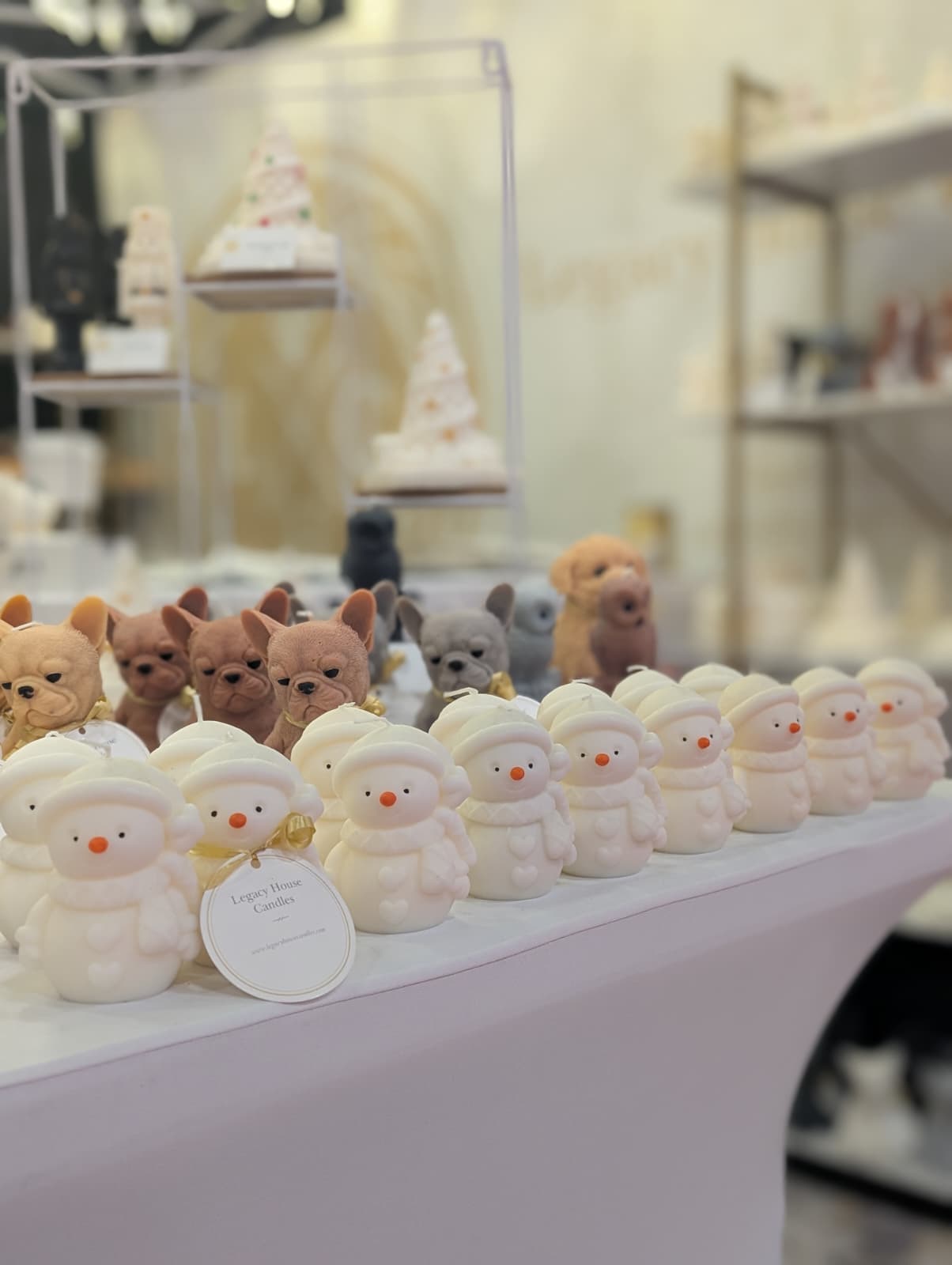 Long row of small snowman candles with french bulldog candles behind