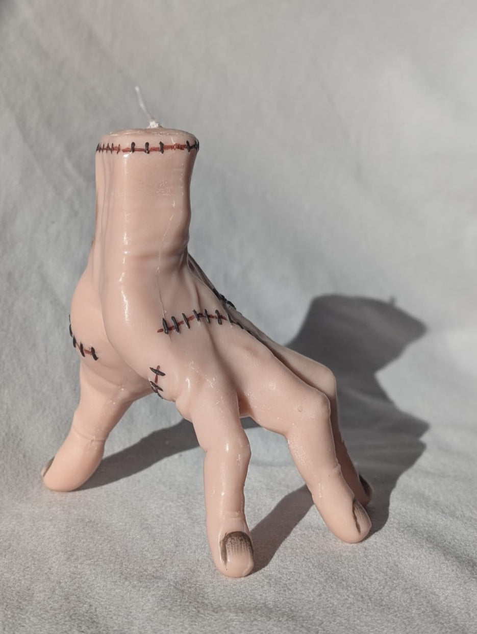Candle shaped like a hand with bandages on a gray surface