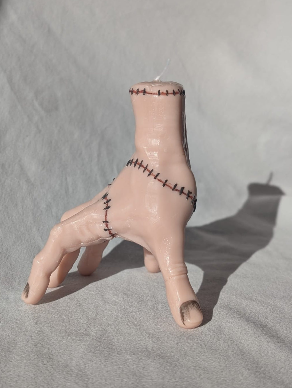 Hand candle with stitched wounds on a gray background