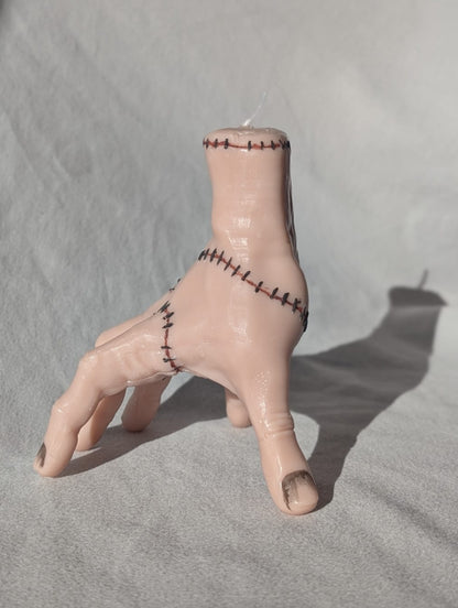 Hand candle with stitched wounds on a gray background
