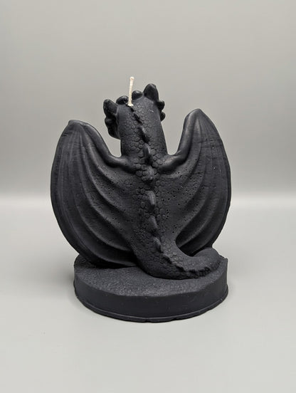 Black dragon-shaped candle on a gray background