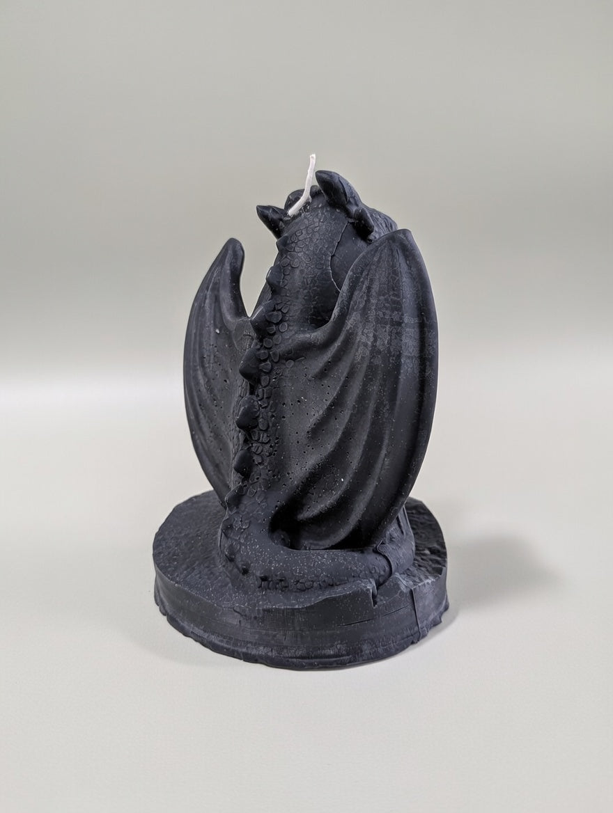 Black dragon-shaped candle on a gray background
