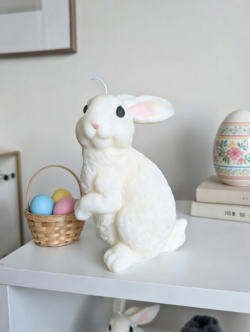 White fuzzy rabbit candle with Easter eggs on a shelf