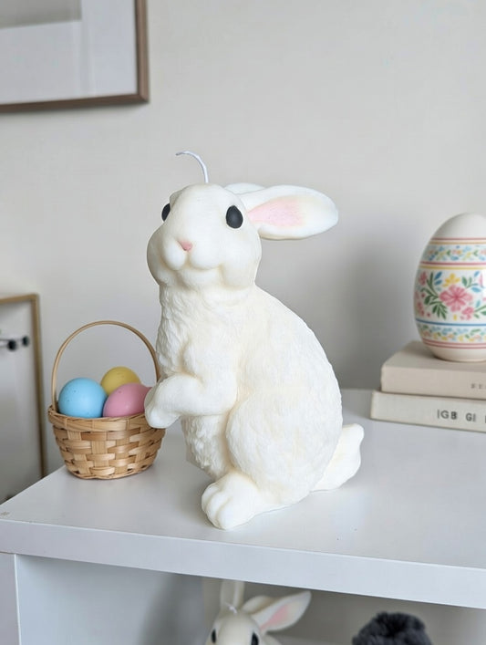 White fuzzy rabbit candle with Easter eggs on a shelf
