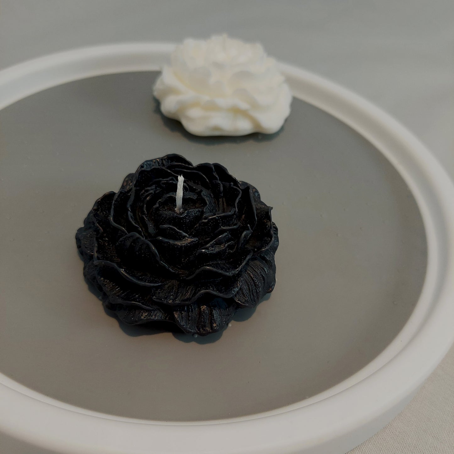 Perspective view of 1 one Peony Flower Candle and 1 black Peony Flower Candle 