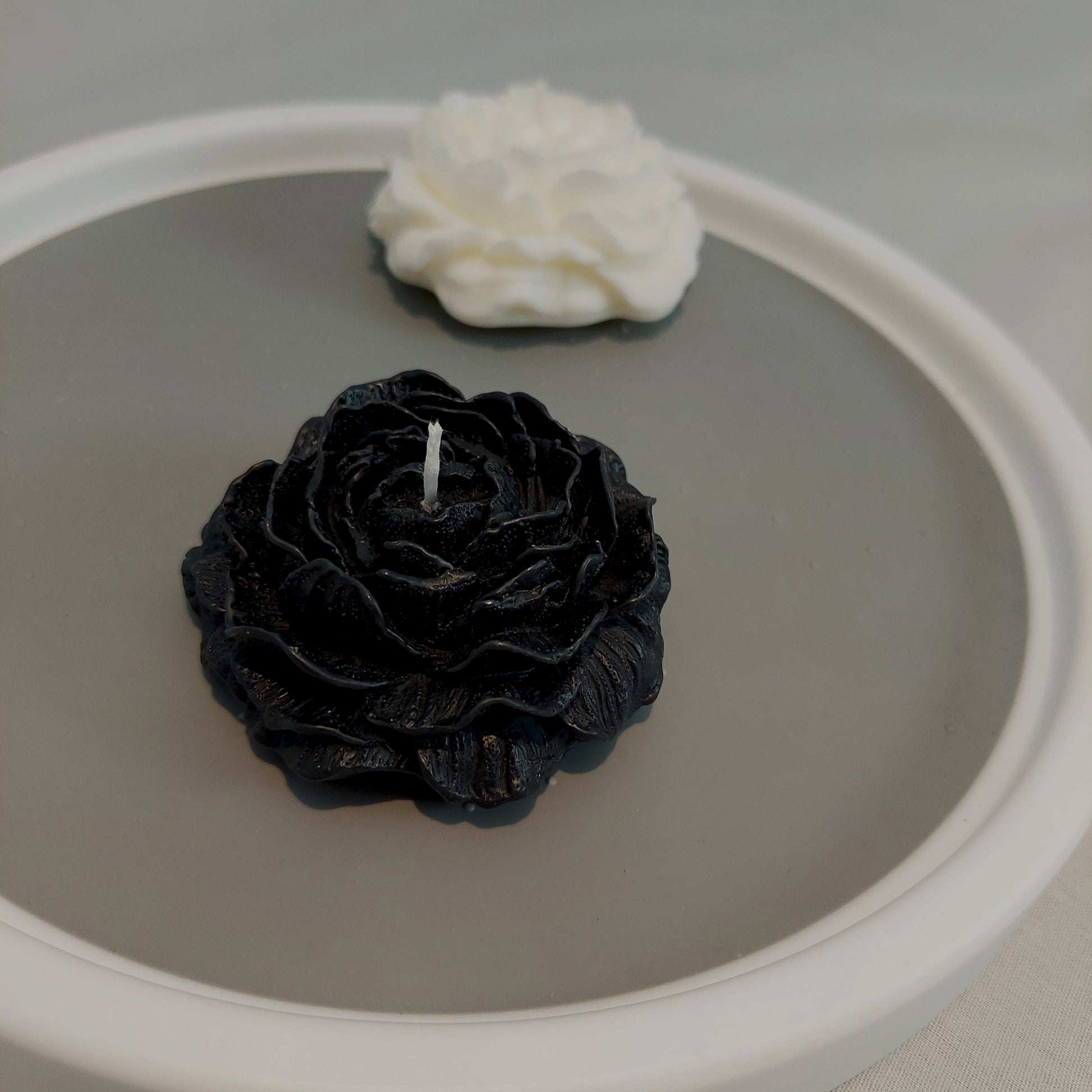 Perspective view of 1 one Peony Flower Candle and 1 black Peony Flower Candle 